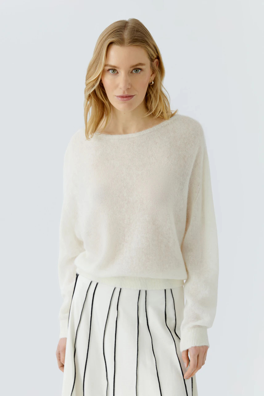 Damen-Pullover: Frau im weißen Pullover mit gestreiftem Rock, lässiger Look.