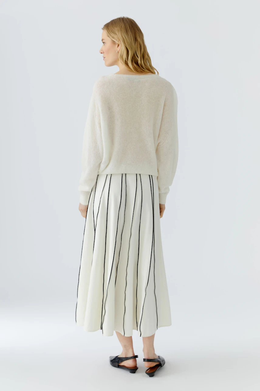 Frau im weißen Pullover und gestreiftem Rock, Rückenansicht. Schlichtes Design für lässigen Look.