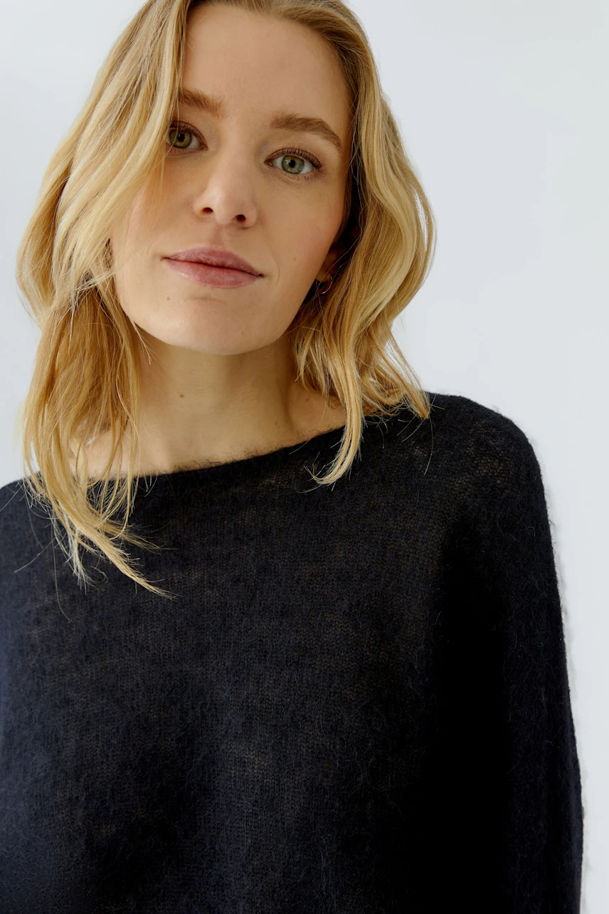 Damen-Pullover: Frau im schlichten schwarzen Pullover mit lässigem Look und natürlichem Ausdruck.