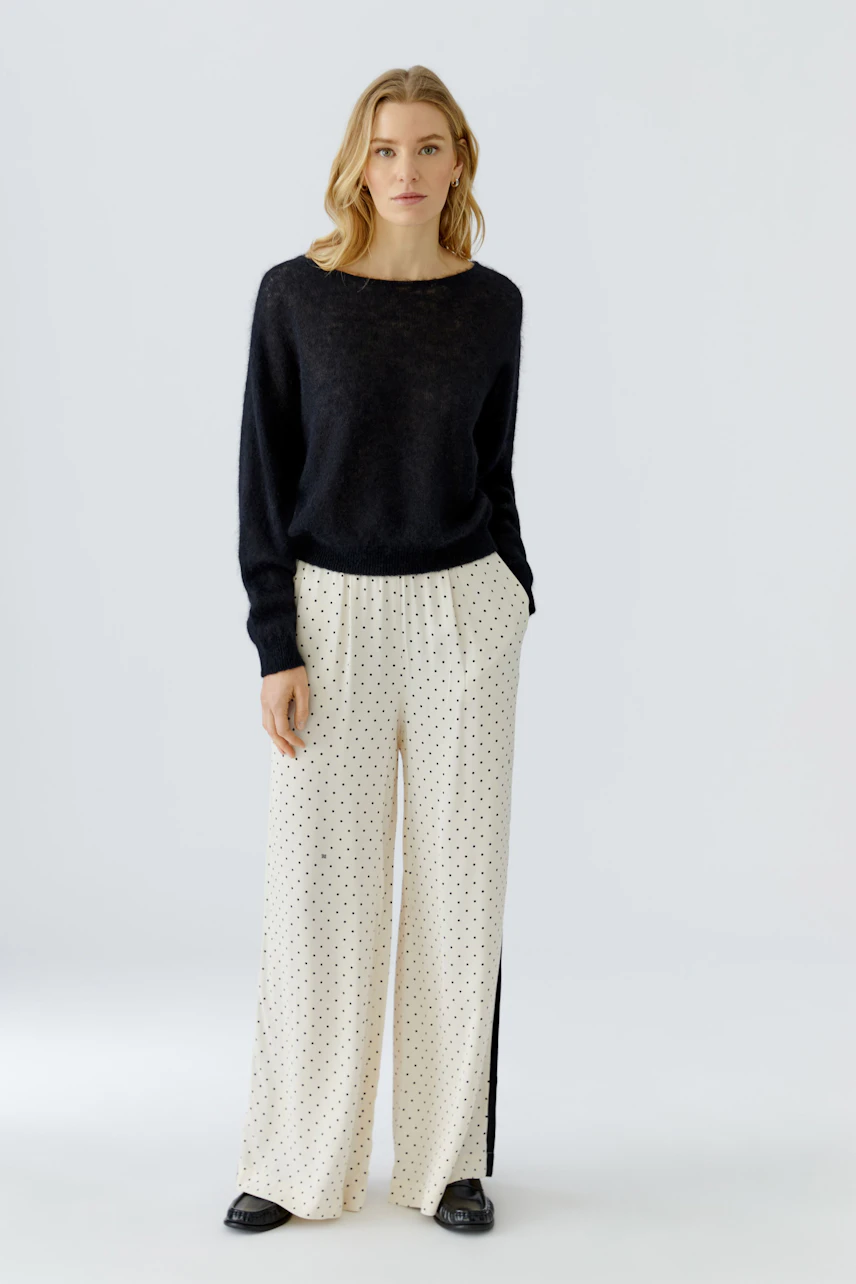 Damen-Pullover: Frau im schwarzen Pullover und gepunkteter Hose, lässig und modern.