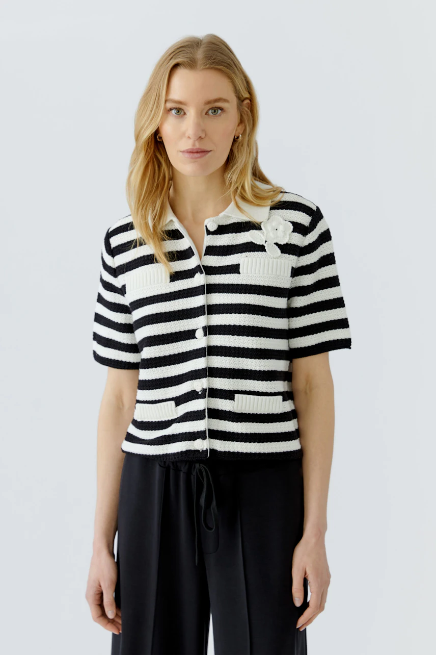 Striped cardigan: Woman in black and white striped cardigan with short sleeves and button front.