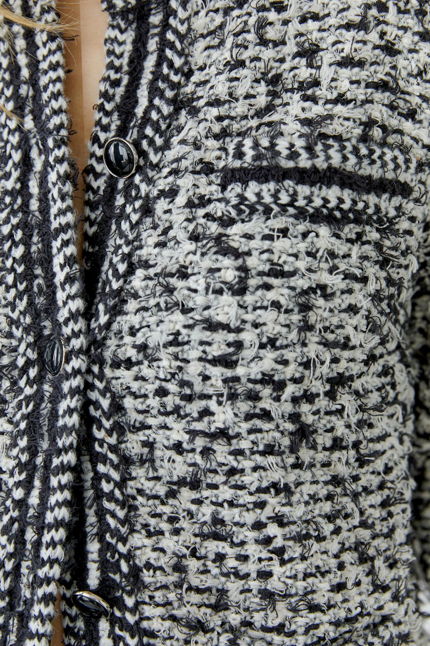Textured knit cardigan: Close-up of black and white pattern with buttons, showcasing intricate design.