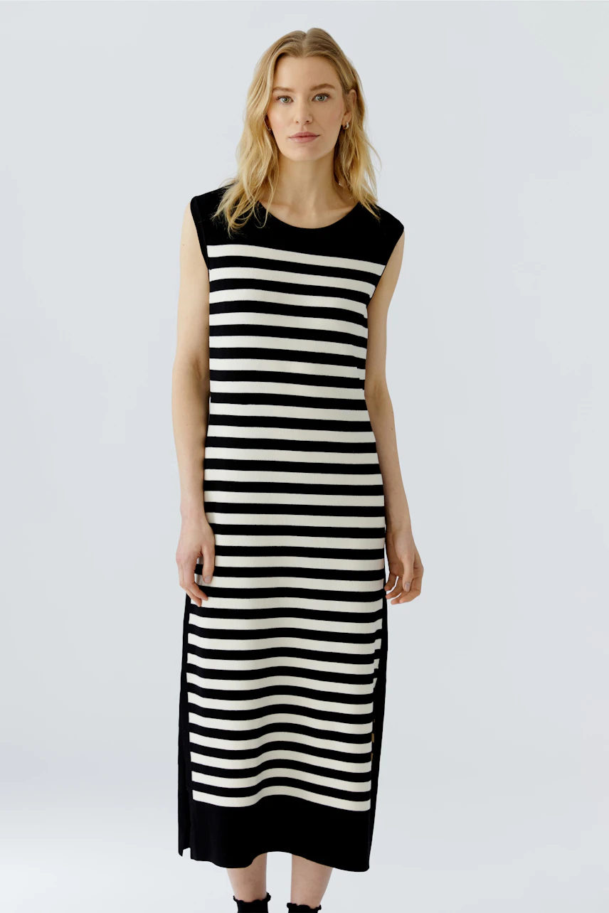 Striped dress: Woman in a sleeveless black and white striped dress, standing confidently.