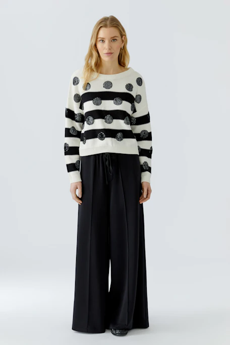 Weißer Damen-Pullover mit schwarzen Streifen und Punkten, lässig und modern.