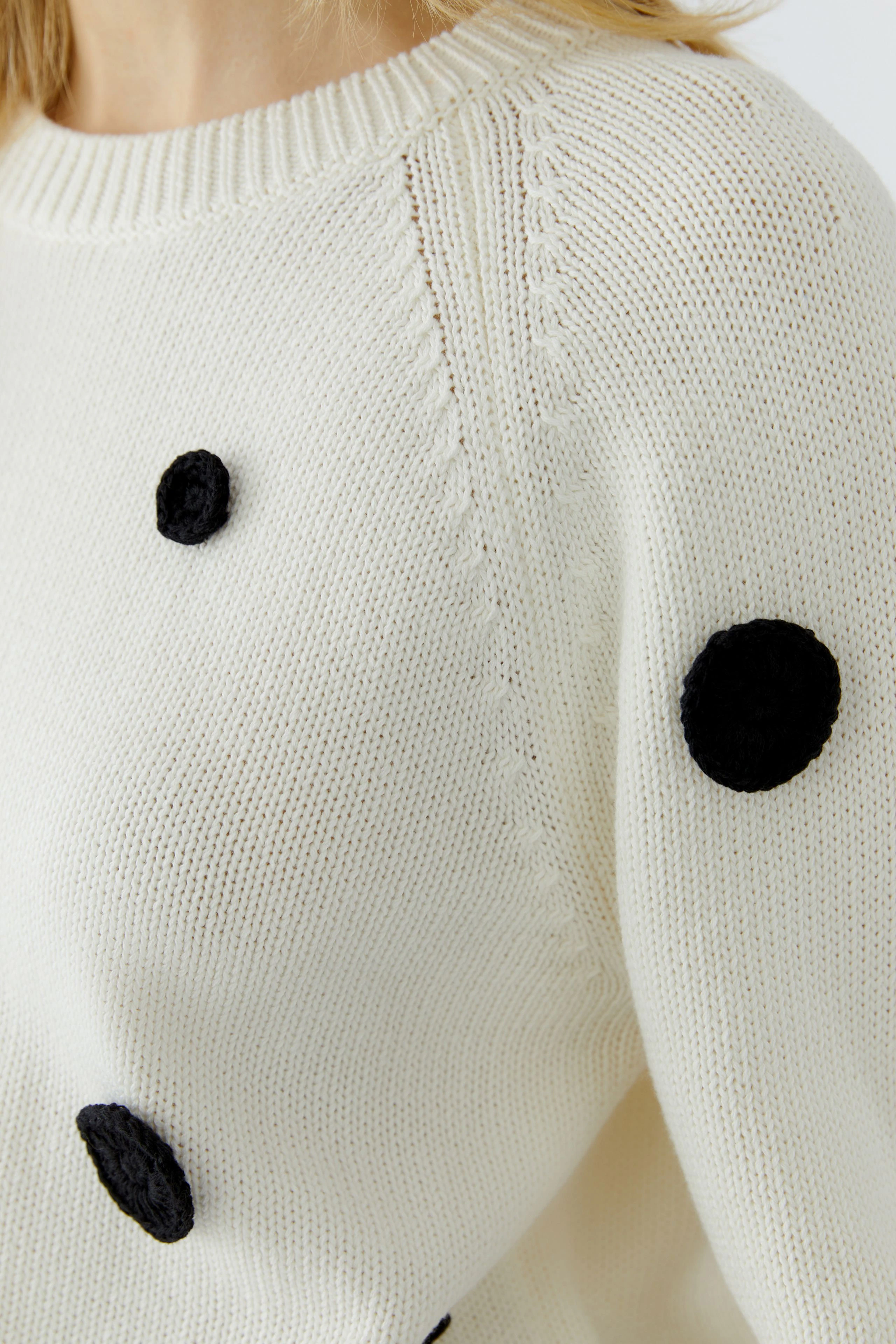 Damen-Pullover: Frau im cremefarbenen Pullover mit schwarzen Punkten, lässig und modern.