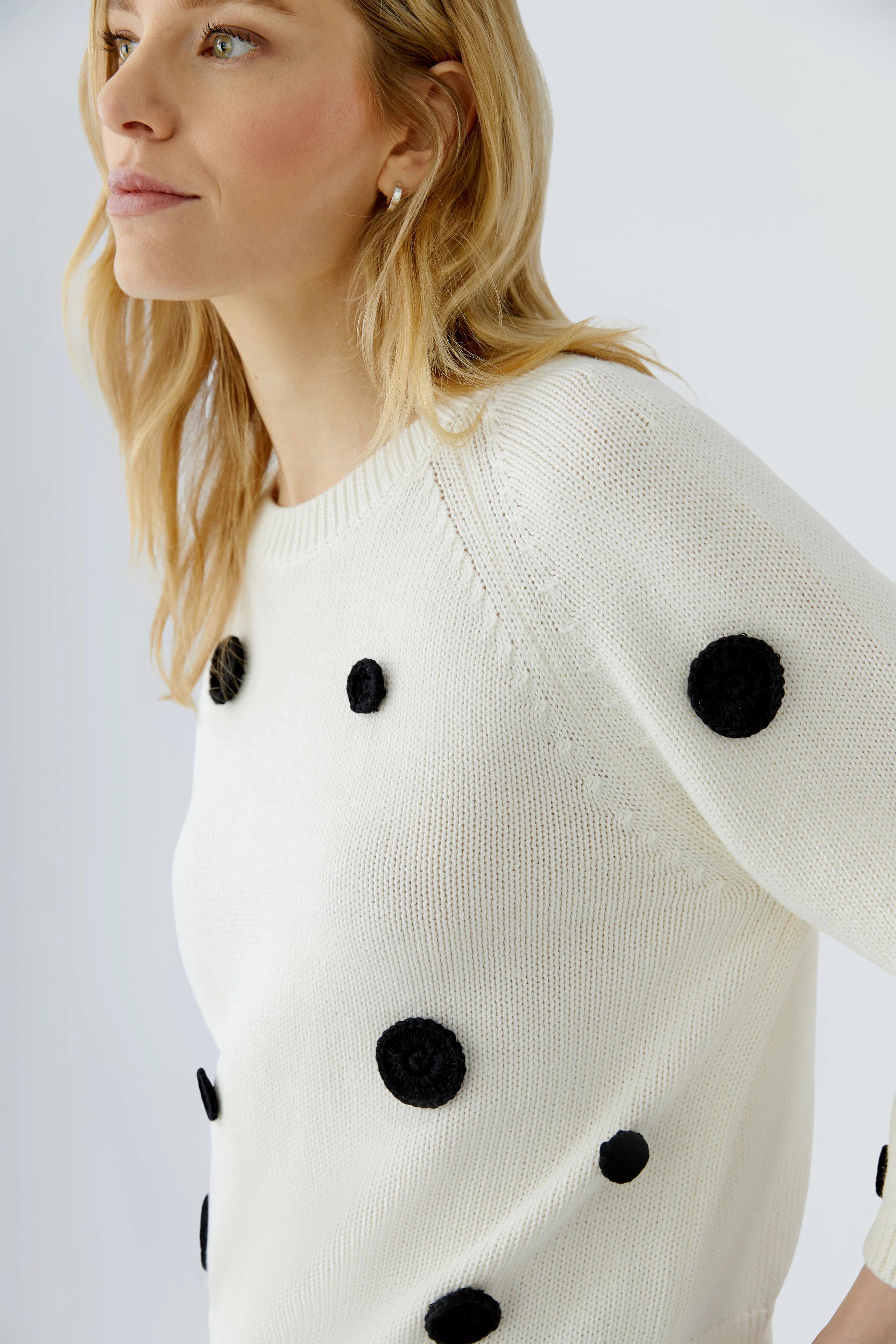 Damen-Pullover: Frau im weißen Pullover mit schwarzen Punkten, lässiger Look.