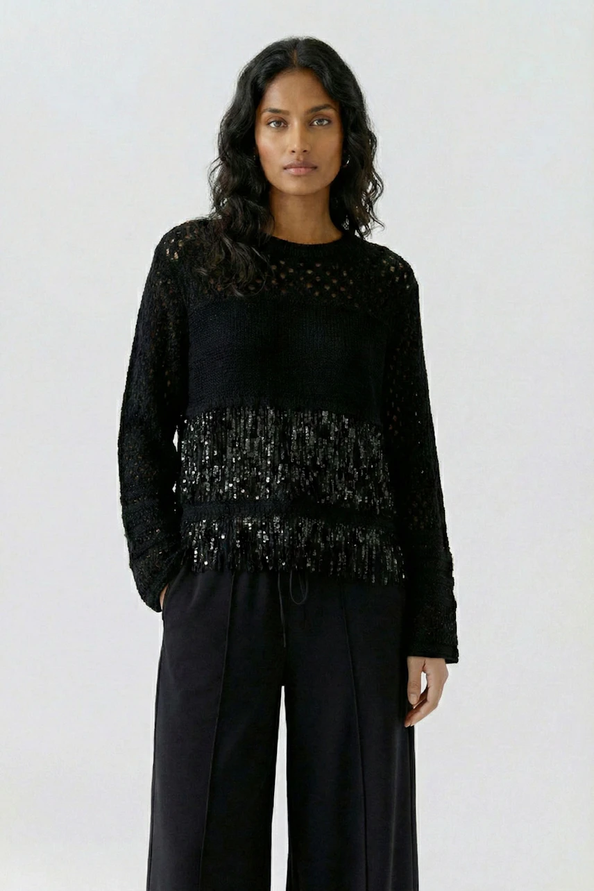 Casual women's pullover: Woman in black textured pullover with subtle fringe detail, paired with wide-leg pants.