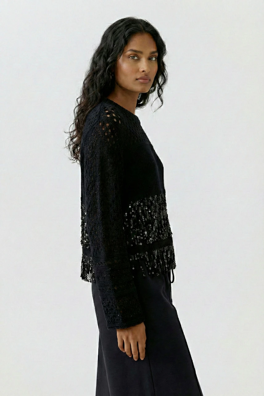 Woman in a black pullover with textured details, standing confidently. Casual and stylish look.