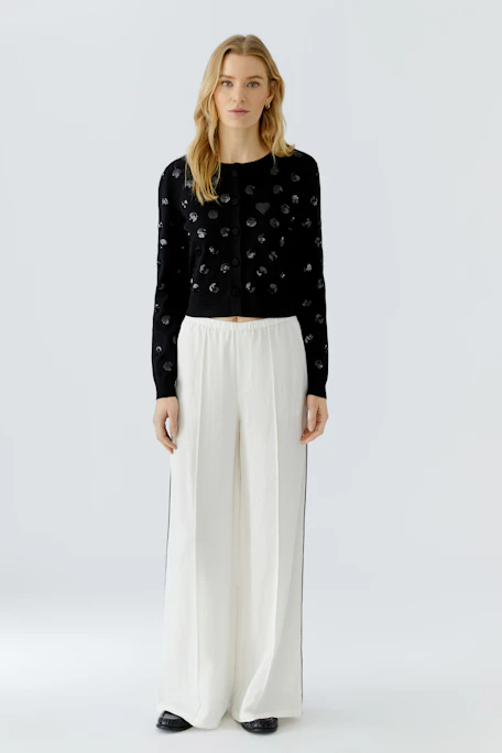 Black cardigan with polka dots, no model. Simple, stylish design for versatile wear.