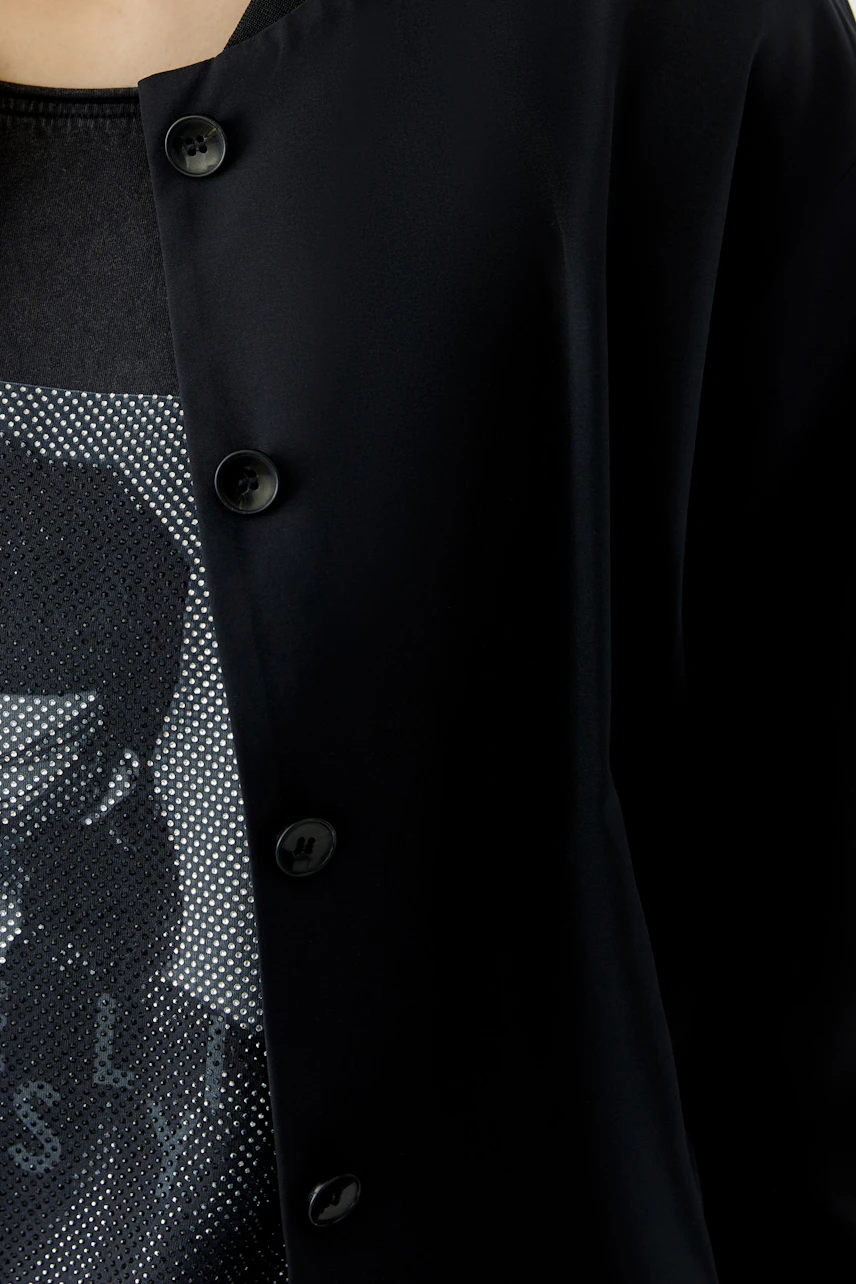 Woman in a black blouson over a graphic tee, showcasing a casual and modern style.