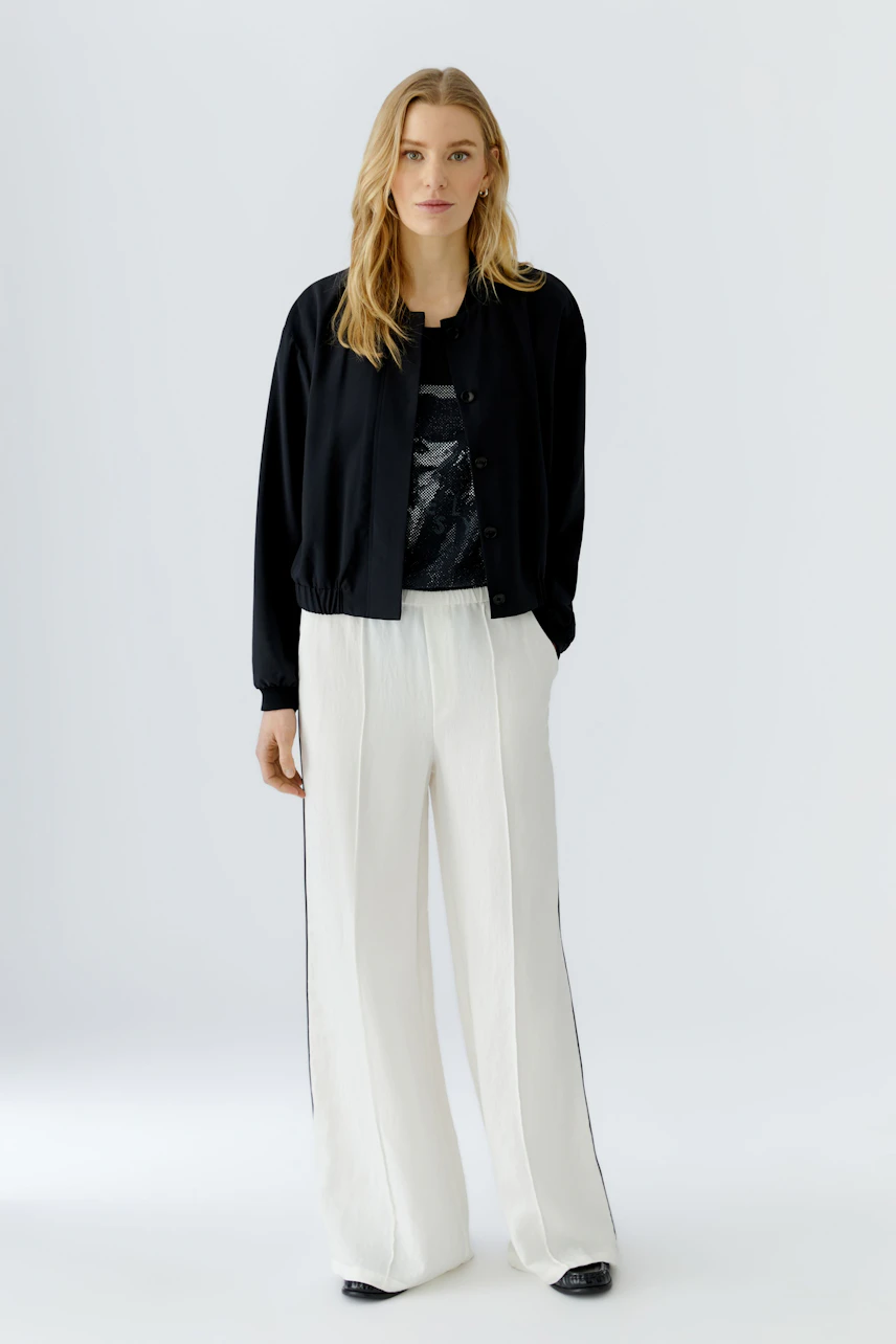 Casual blouson: Woman in a black blouson with a relaxed fit, paired with white wide-leg pants.