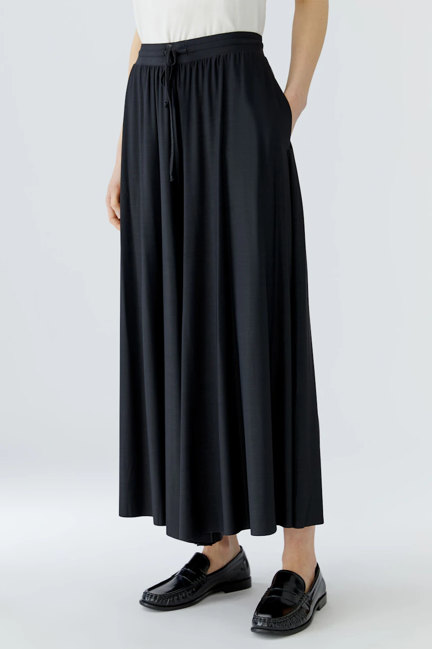 Casual culotte: Woman in a black wide-leg culotte with a relaxed fit, paired with loafers.
