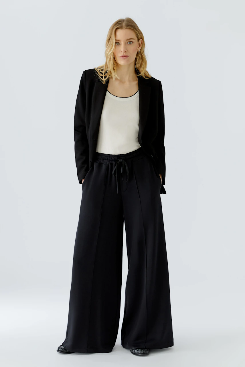 Frau in schwarzer Marlenehose und Blazer, weißes Top. Lässiger Look, ideal für Büro und Freizeit.