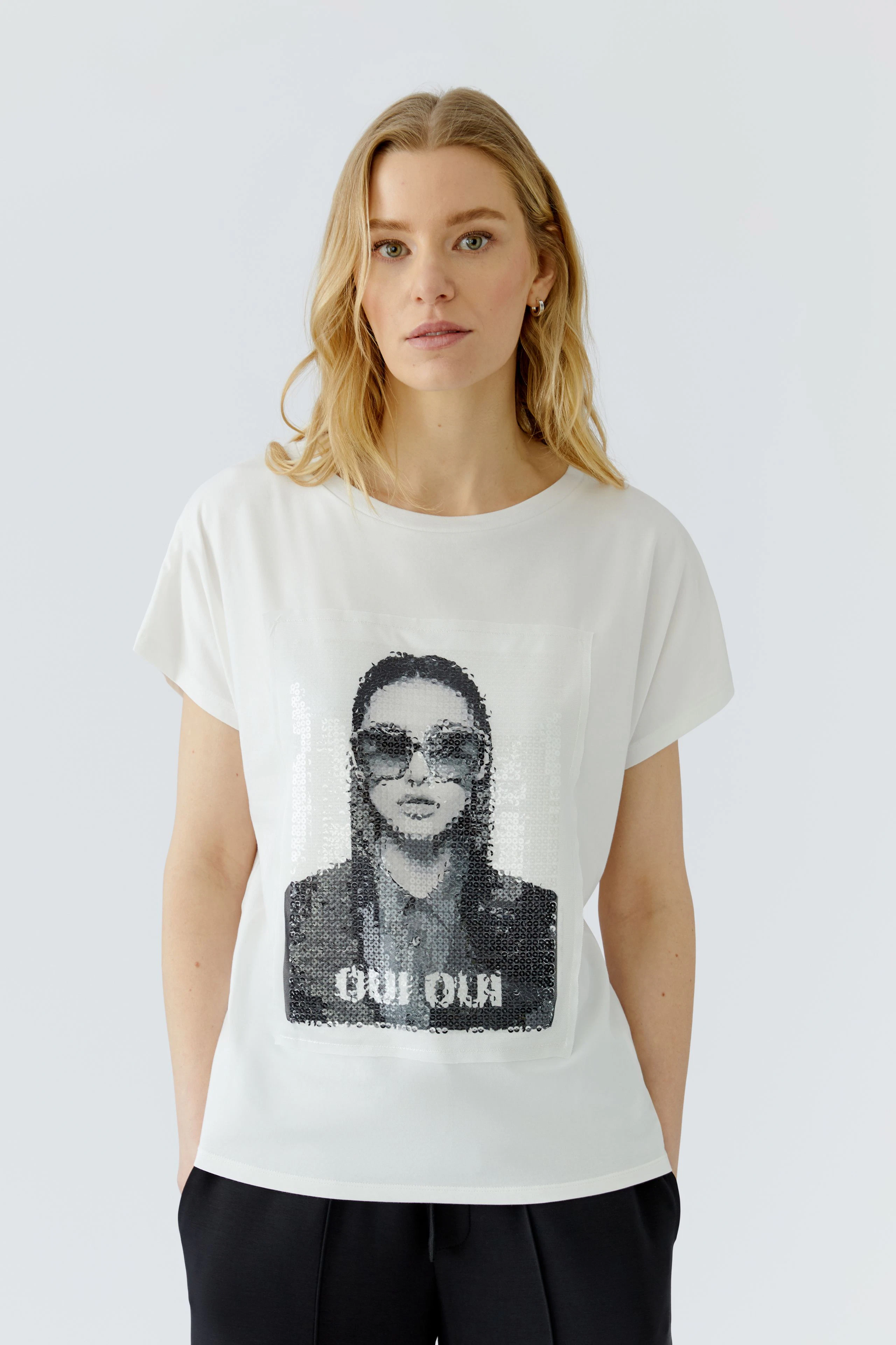 Damen-T-Shirt: Frau im weißen T-Shirt mit auffälligem Print und lässiger Ausstrahlung.