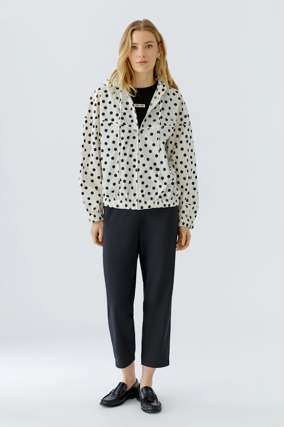 Gepunkteter Blouson: Weißer Blouson mit schwarzen Punkten, Kapuze und elastischem Bund, ohne Model.