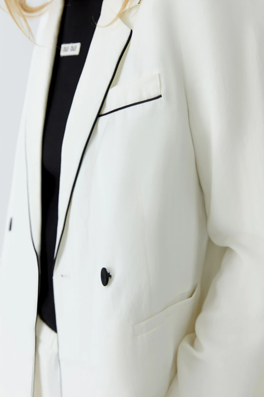 Weißer Damen-Blazer: Frau trägt weißen Blazer mit schwarzem Shirt, schlicht und modern.