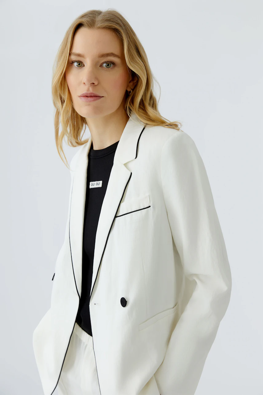 Weißer Damen-Blazer: Frau im weißen Blazer mit schwarzem Shirt, lässiger Look.
