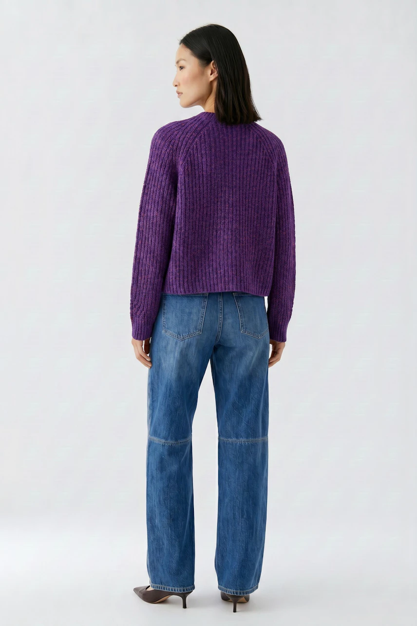 Casual cardigan: Woman in purple knit cardigan and blue jeans, standing confidently.