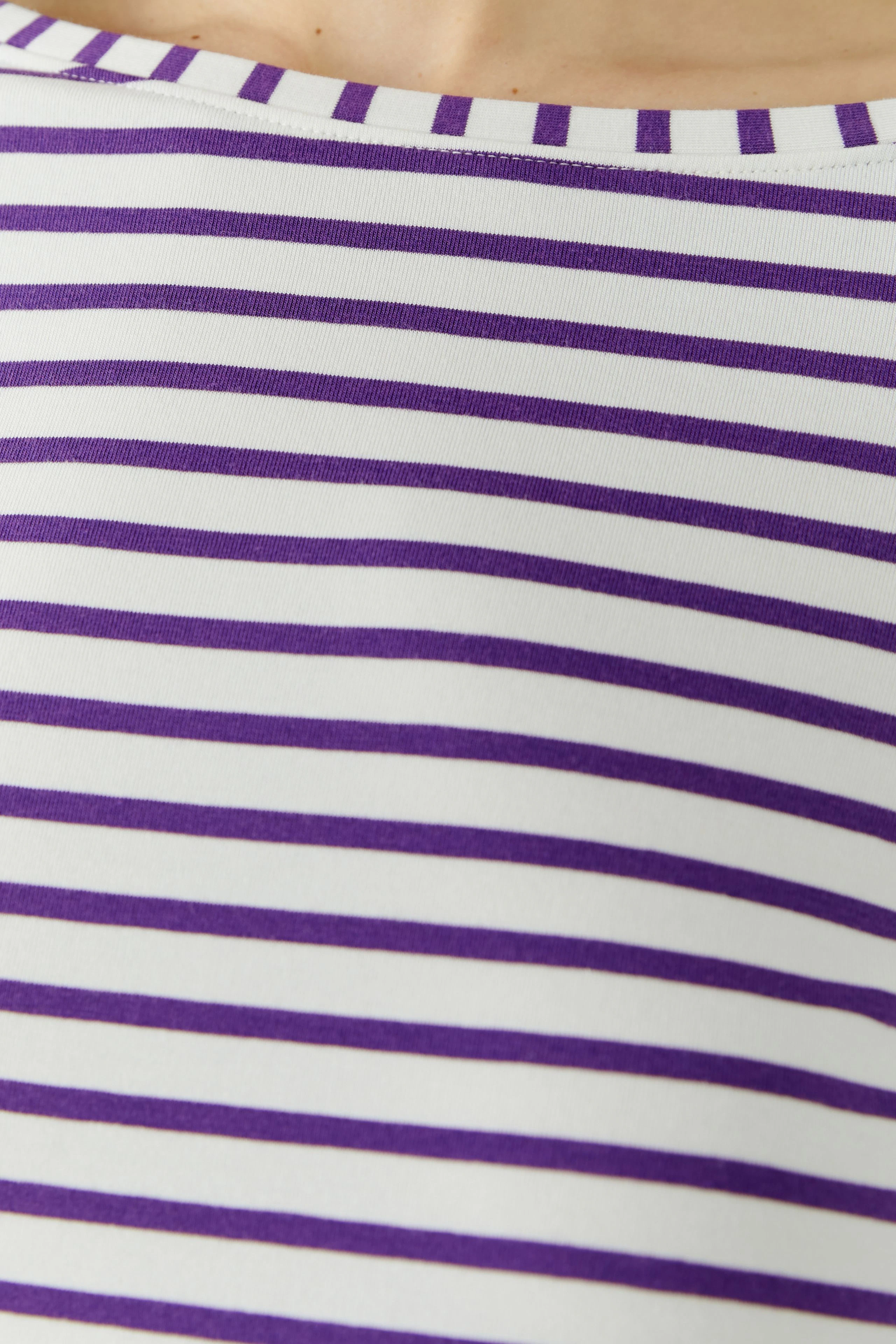 Striped long-sleeve shirt: Close-up of purple and white stripes on fabric, showcasing casual style.