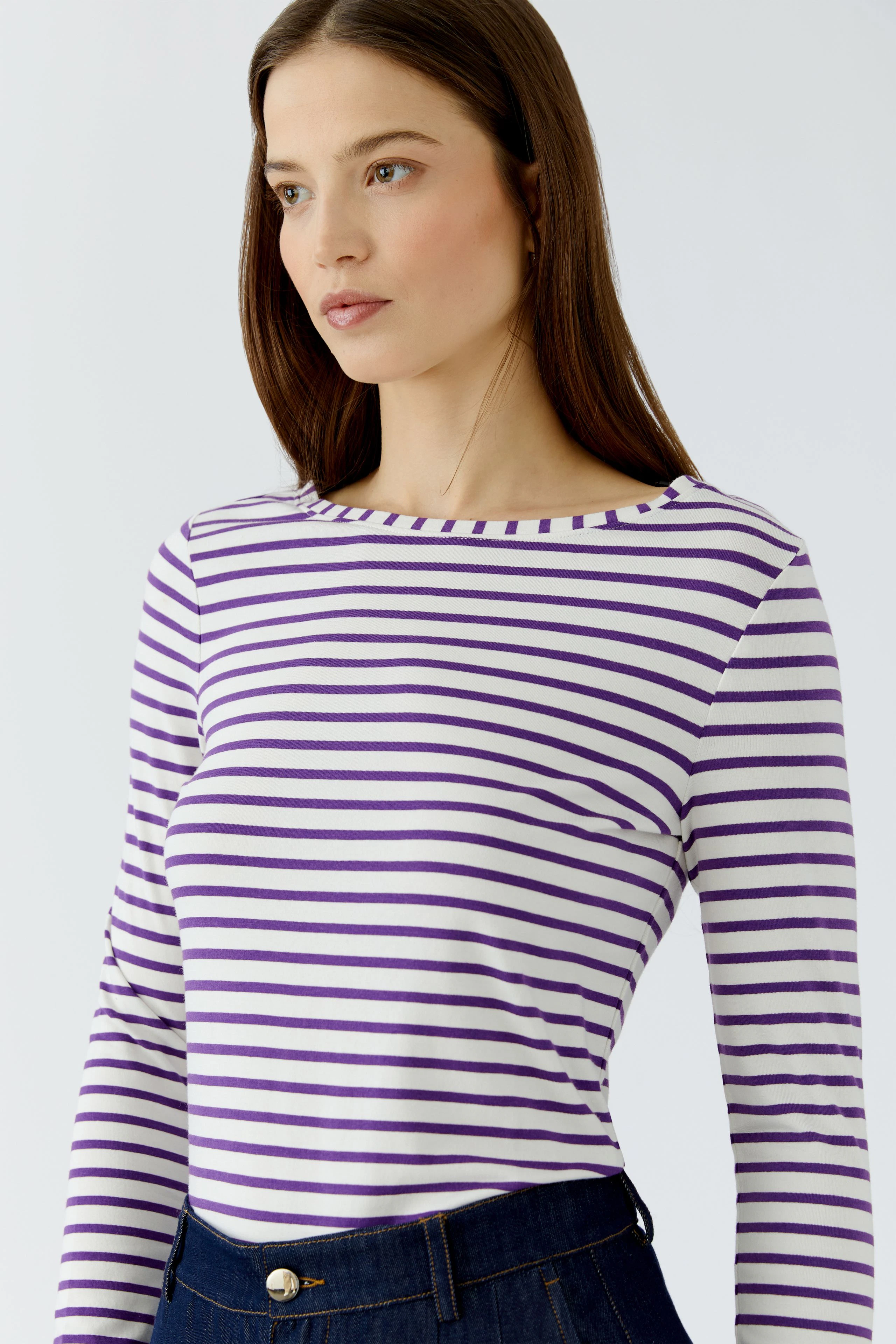 Striped long-sleeve shirt: Woman in purple and white striped shirt, casual and stylish.