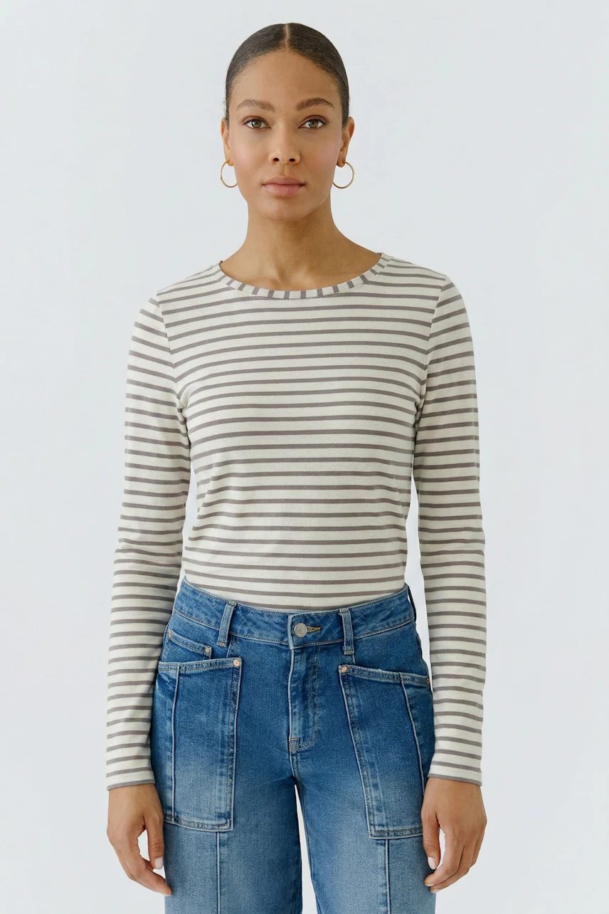 Gestreiftes Langarmshirt: Frau trägt ein gestreiftes Shirt mit blauen Jeans, schlicht und modern.