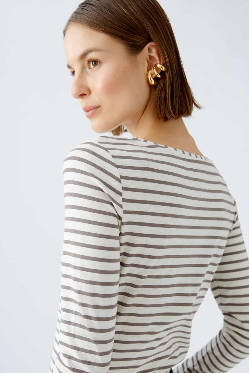 Gestreiftes Langarmshirt: Frau mit kurzen Haaren trägt ein lässiges, gestreiftes Shirt und goldene Ohrringe.