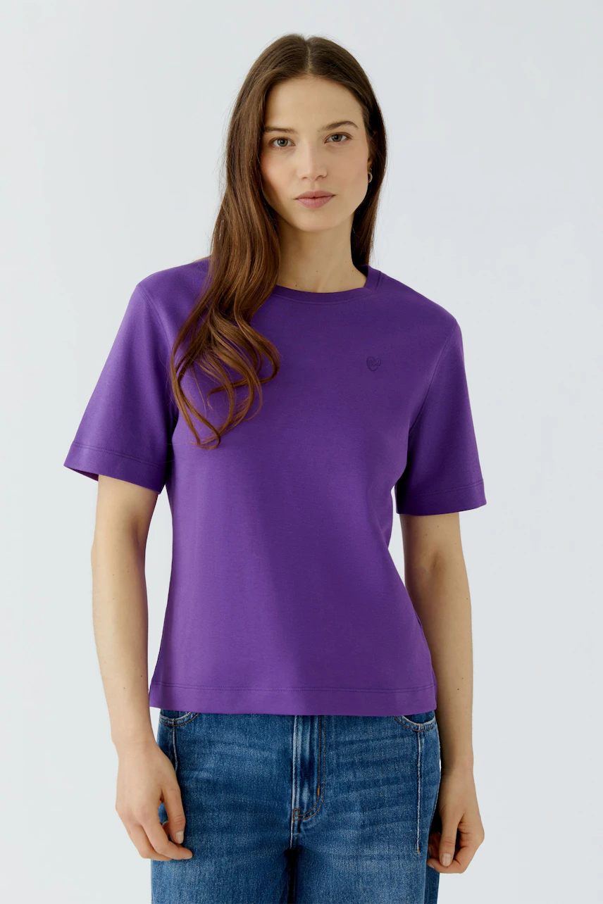 Lässiges Damen-T-Shirt: Frau im lila T-Shirt und blauen Jeans, schlicht und modern.