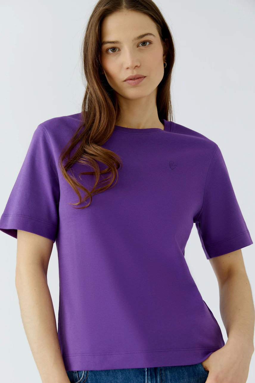 Lila Damen-T-Shirt: Frau im schlichten T-Shirt mit kurzen Ärmeln und lockerer Passform.