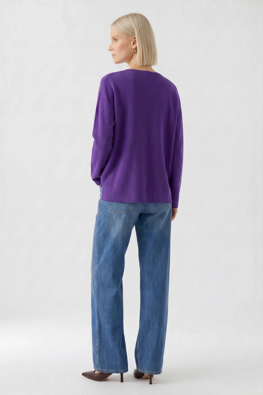 Casual women's pullover: Woman in a purple pullover and blue jeans, standing confidently.