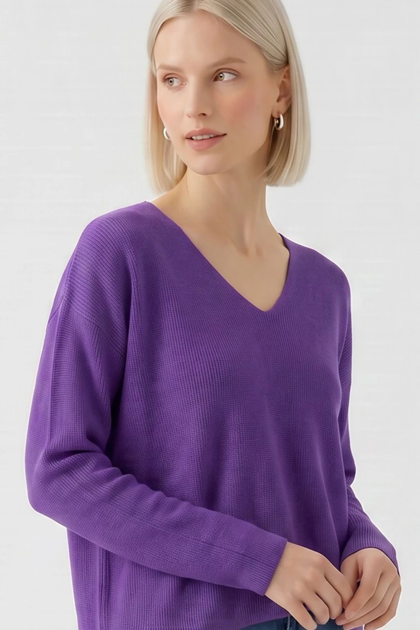 Woman in a vibrant purple pullover with V-neck, looking to the side, showcasing casual style.