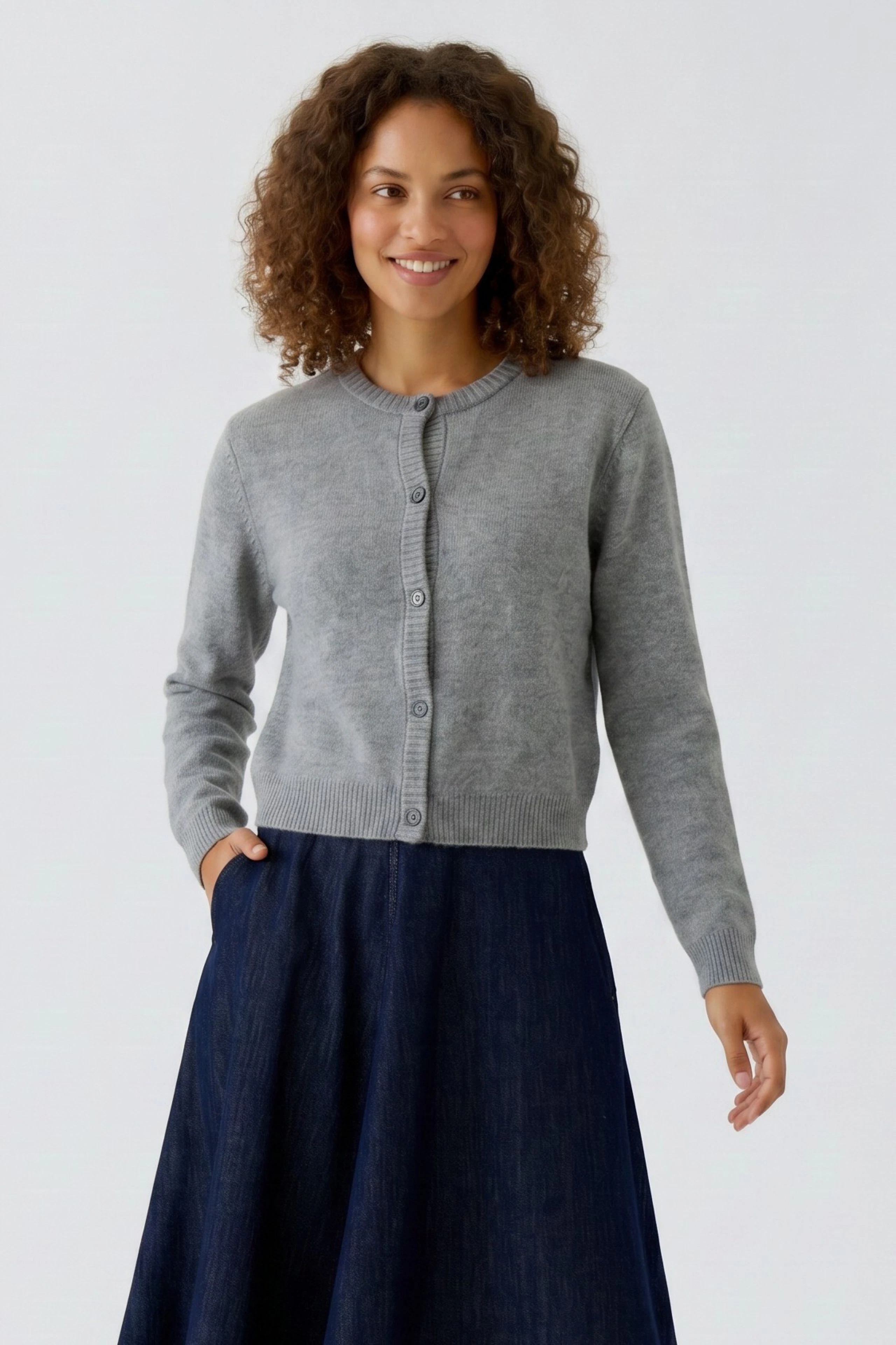 Casual women's cardigan: Woman in a grey knit cardigan with buttons, paired with a dark skirt, smiling.