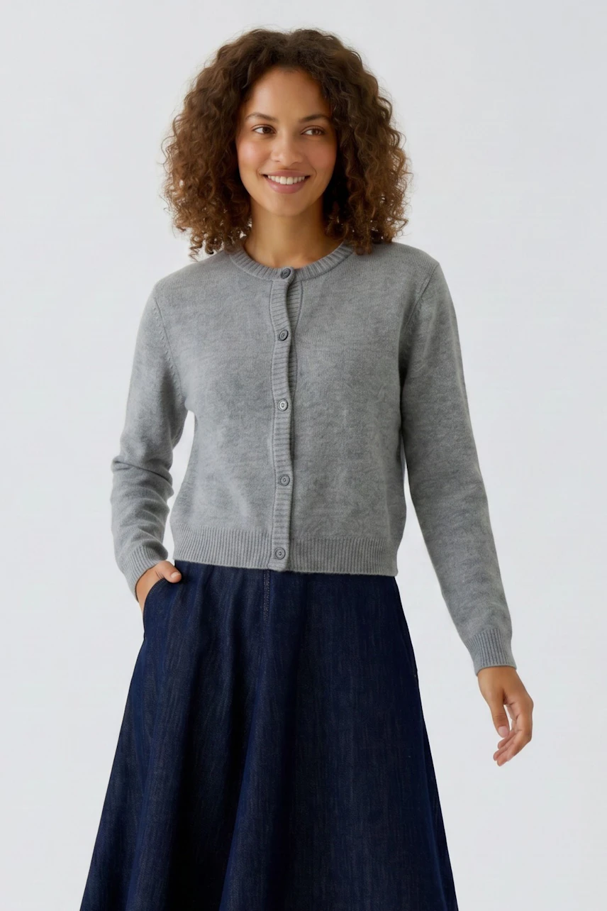 Casual women's cardigan: Woman in a grey knit cardigan with buttons, paired with a dark skirt, smiling.
