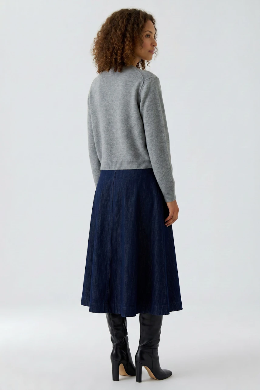 Casual knit cardigan: Woman in a grey cardigan, navy skirt, and black boots, standing confidently.