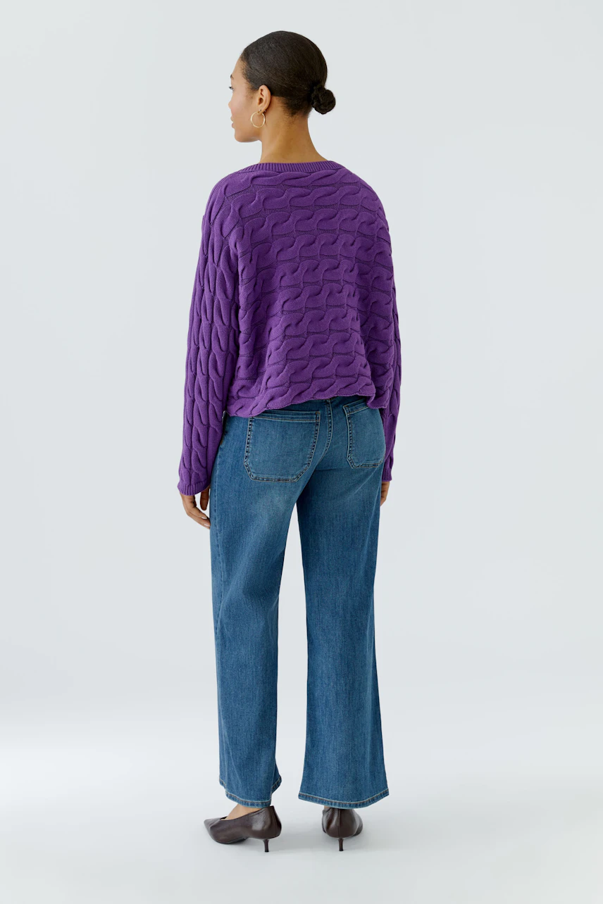 Lässiger Damen-Pullover: Frau im lila Pullover und blauer Jeans von hinten, schlicht und modern.