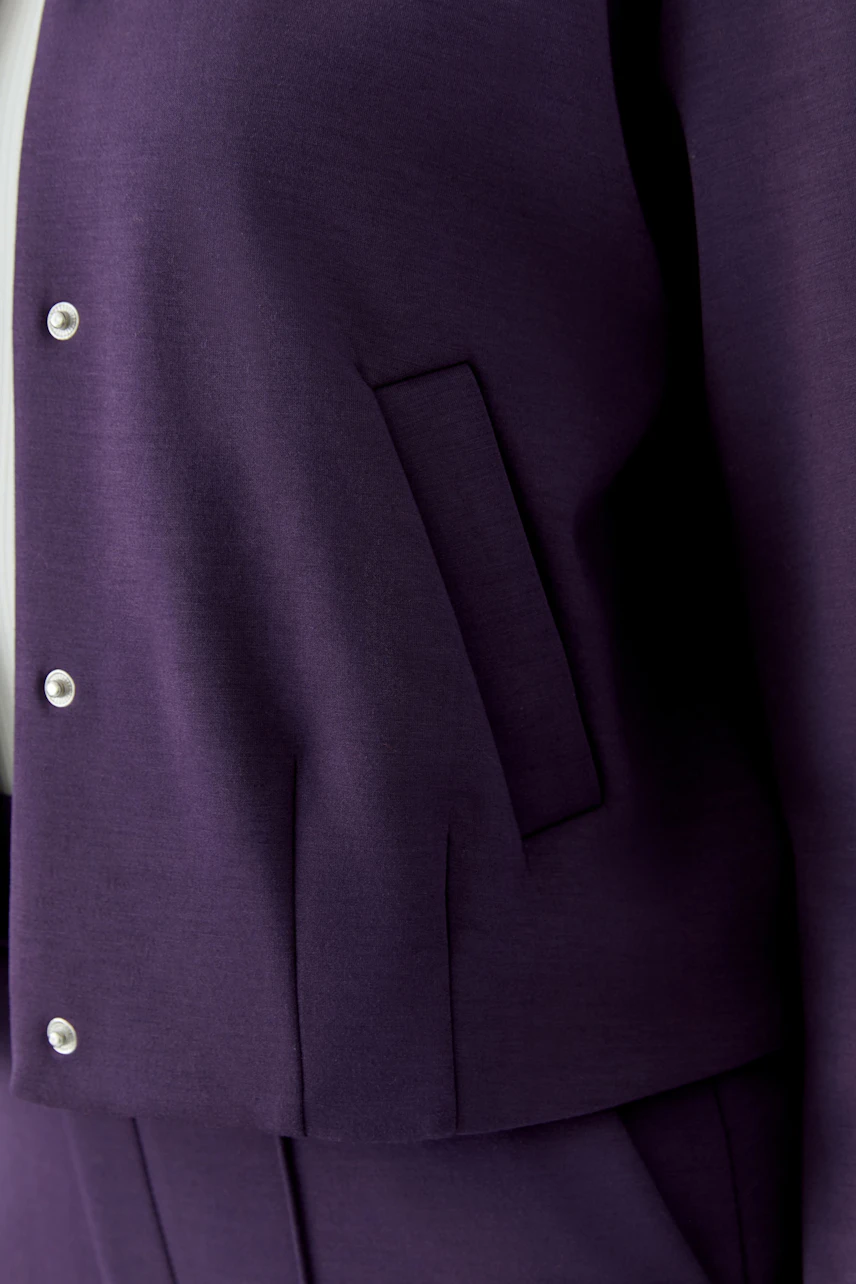 Lila Blouson: Detailaufnahme eines lila Blousons mit Knöpfen und Taschen, ohne Model.