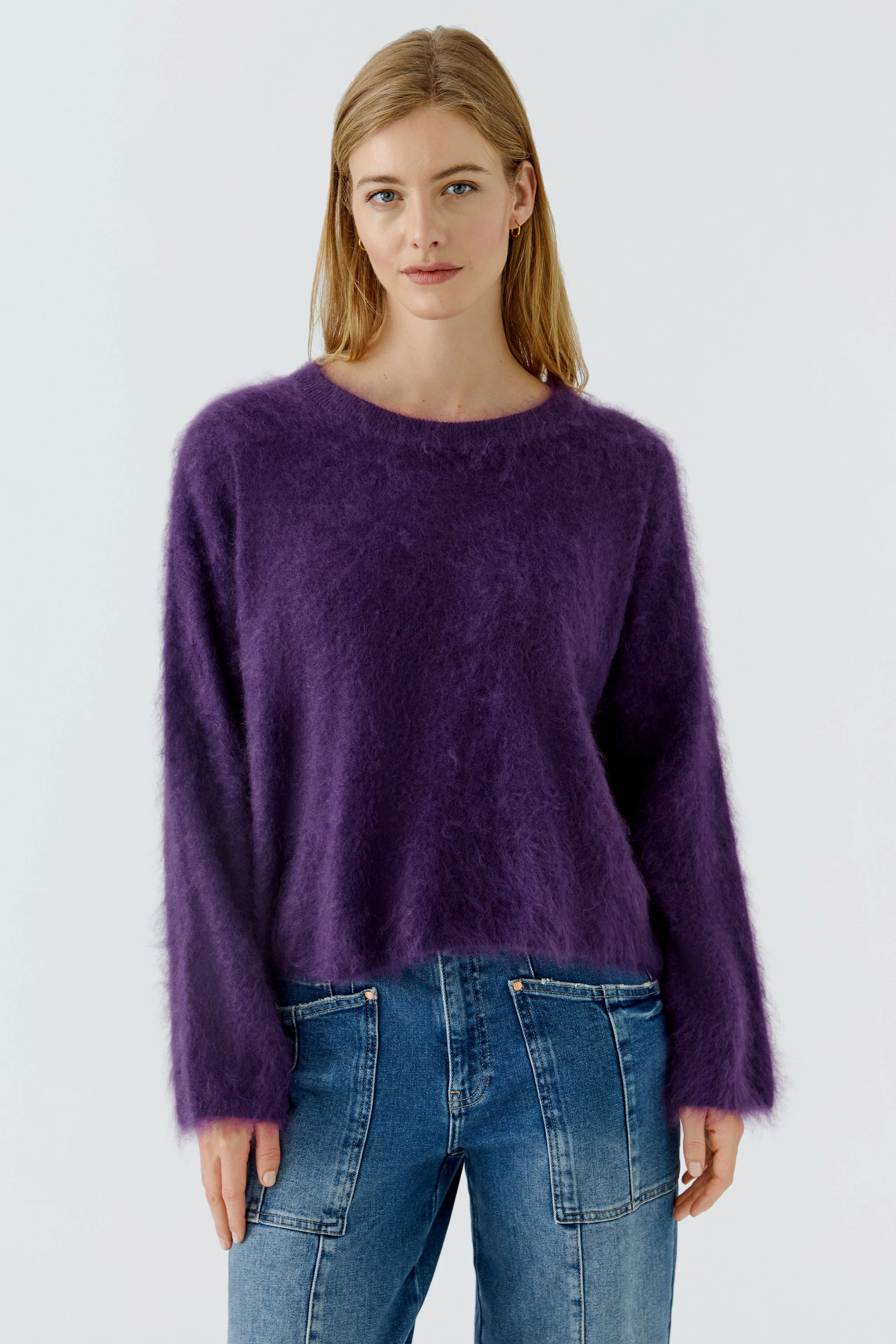 Lässiger Damen-Pullover: Frau im flauschigen lila Pullover und blauen Jeans, entspannt und modisch.