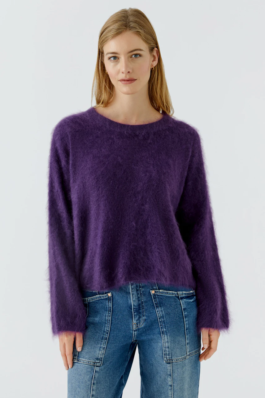 Lässiger Damen-Pullover: Frau im flauschigen lila Pullover und blauen Jeans, entspannt und modisch.