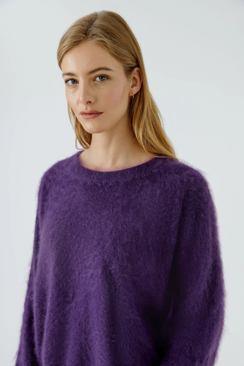 Casual women's pullover: Woman in a cozy purple pullover with a relaxed fit, looking serene.