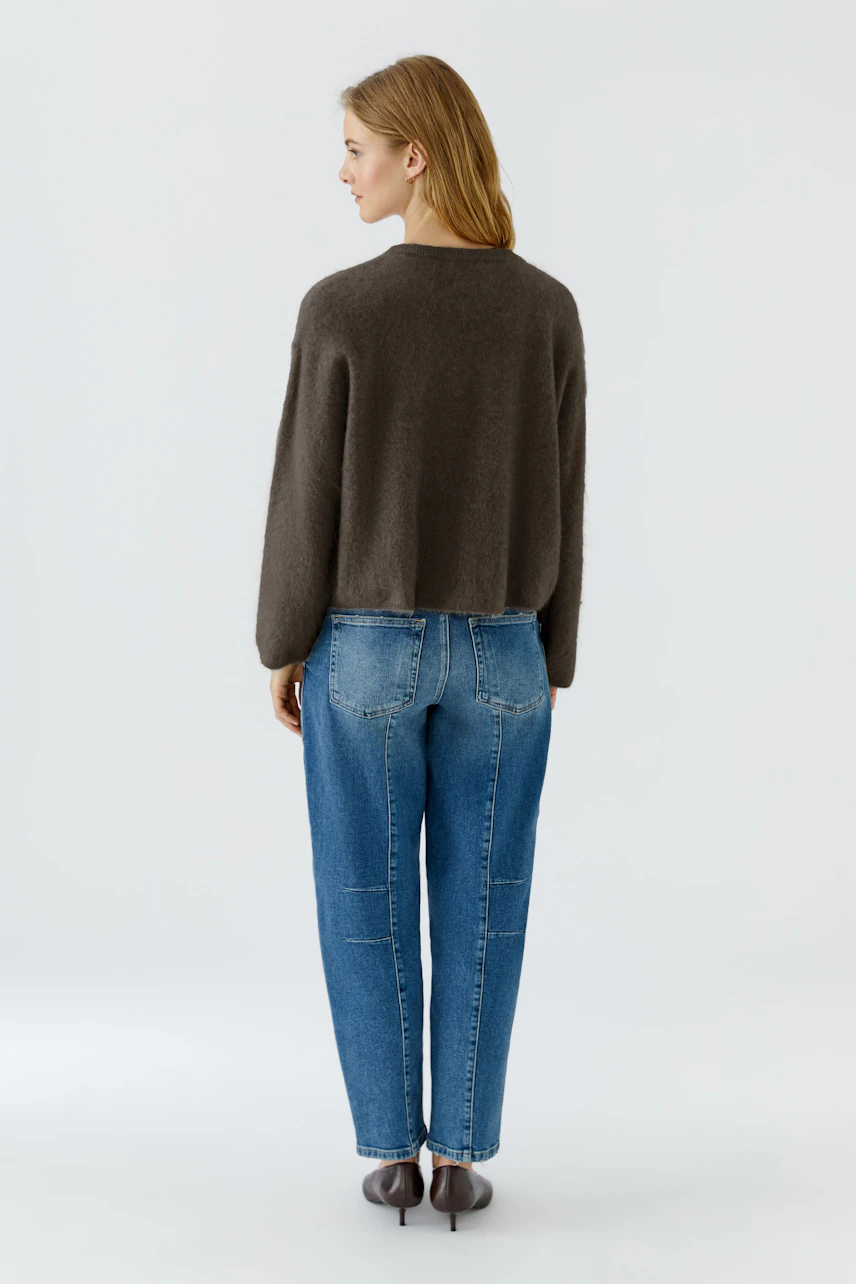 Casual pullover: Woman in a cozy brown pullover and blue jeans, viewed from the back.