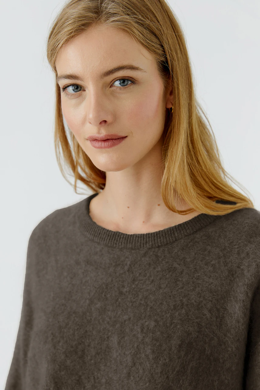 Casual women's pullover: Blonde woman in a soft brown pullover with a relaxed fit, looking serene.