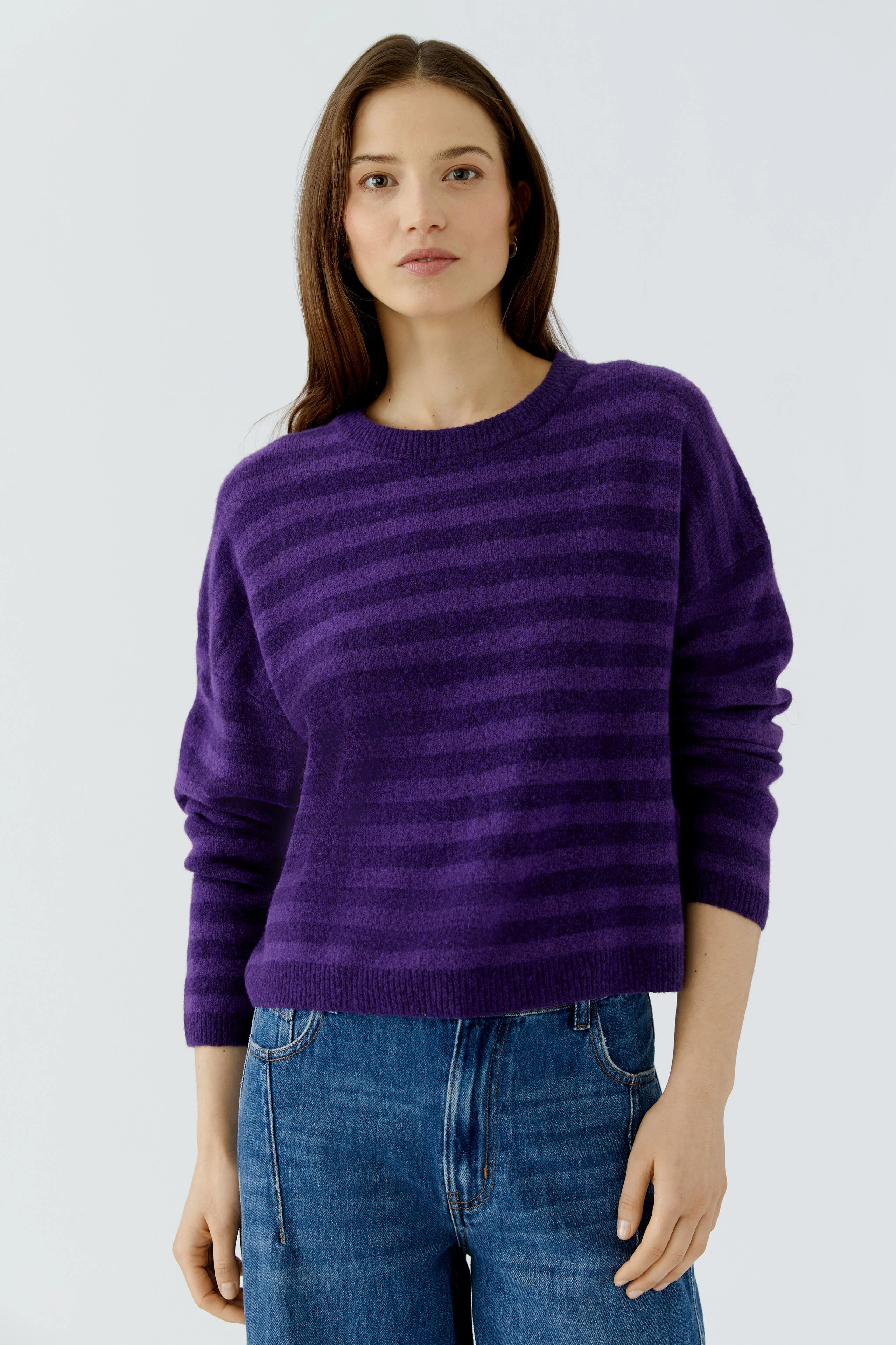 Lässiger Damen-Pullover: Frau im lila gestreiften Pullover und Jeans, schlicht und modern.