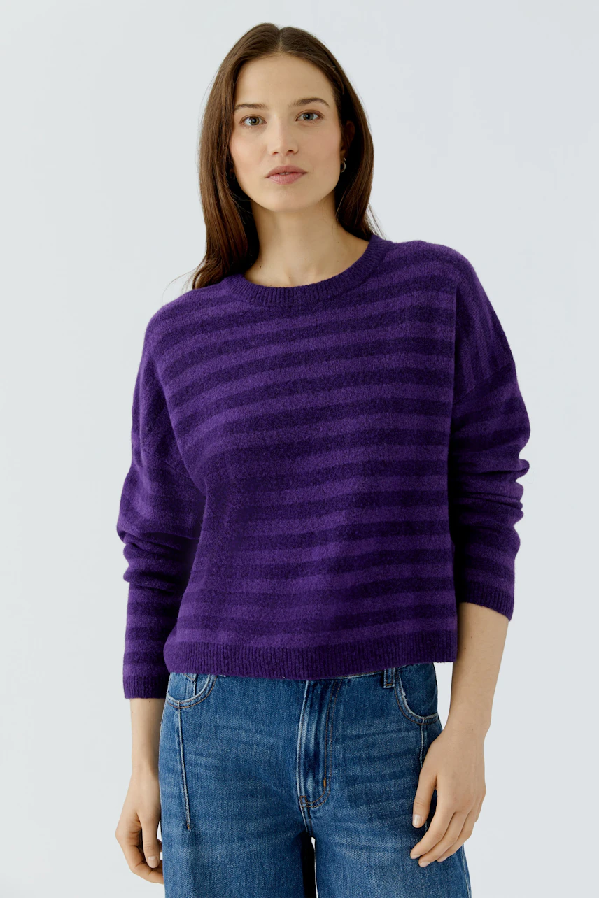 Lässiger Damen-Pullover: Frau im lila gestreiften Pullover und Jeans, schlicht und modern.
