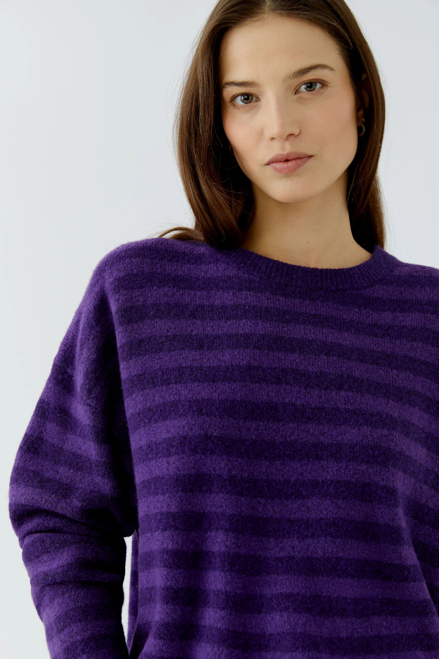 Frau im lila gestreiften Pullover, lässiger Look, weicher Stoff, ideal für kühle Tage.