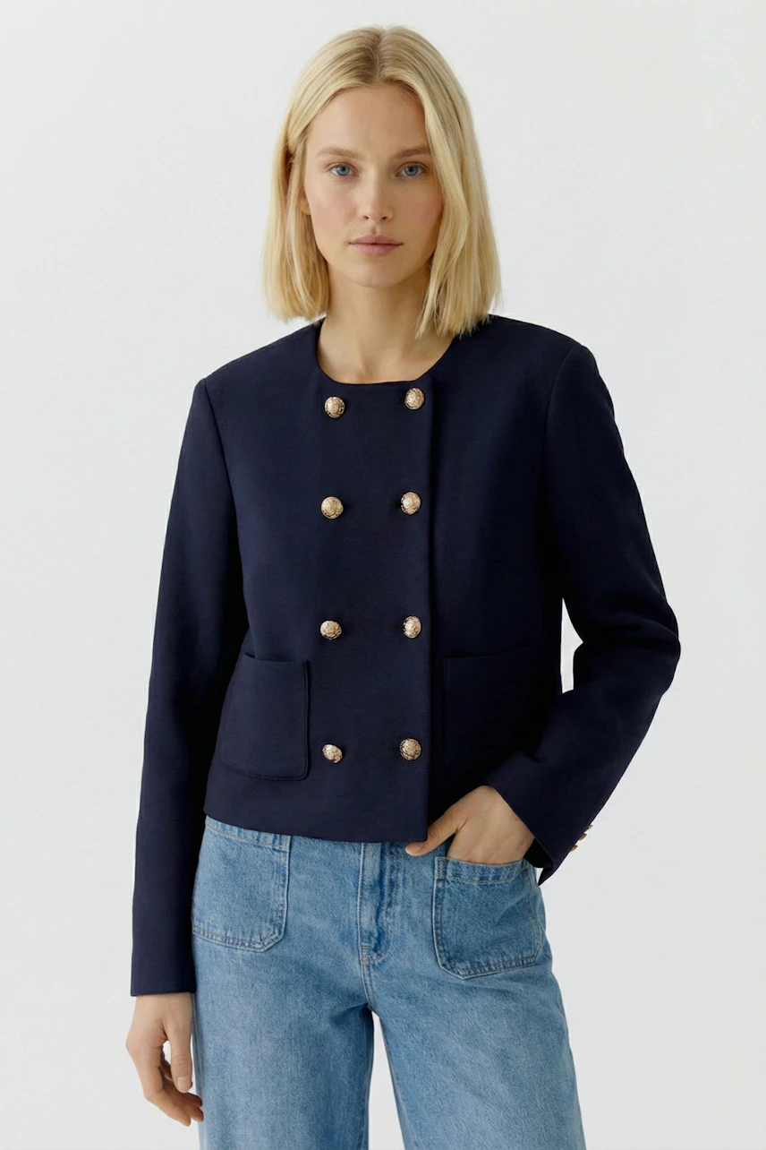 Moderne Damen-Jacke: Frau in navyfarbener Jacke mit goldenen Knöpfen und lässigen Jeans.