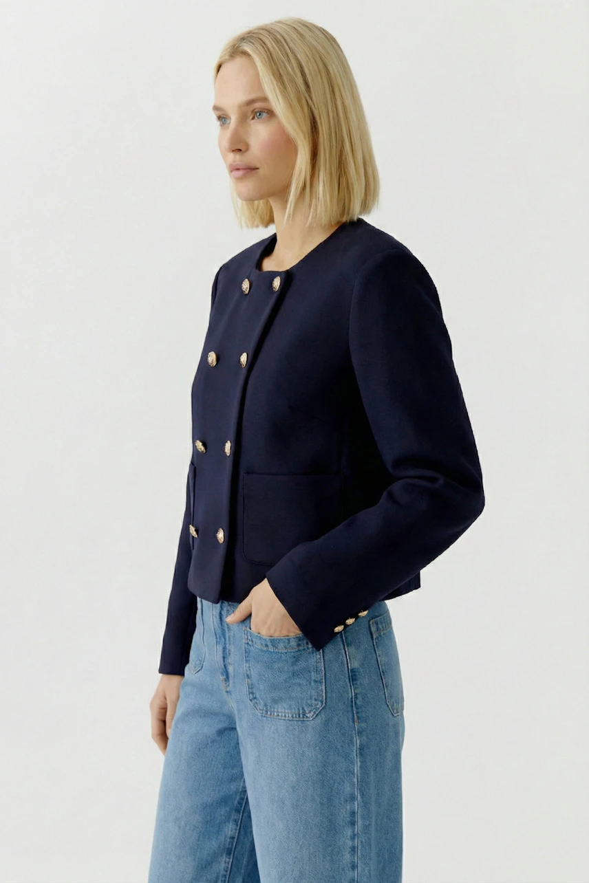 Moderne Damen-Jacke: Frau in navyfarbener Jacke mit goldenen Knöpfen und zwei Taschen.