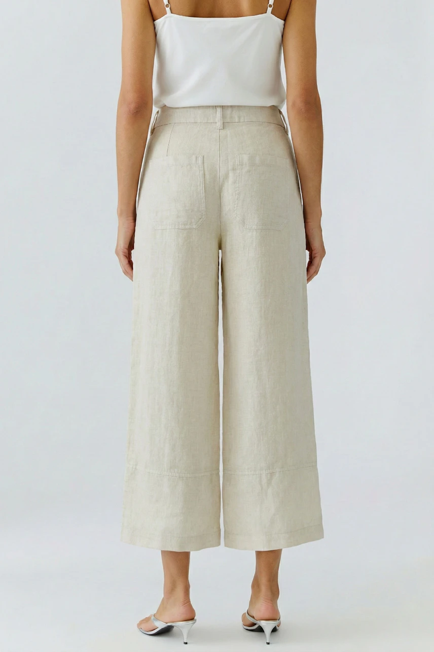 Casual women's trousers: Woman in beige wide-leg trousers and white top, viewed from the back.