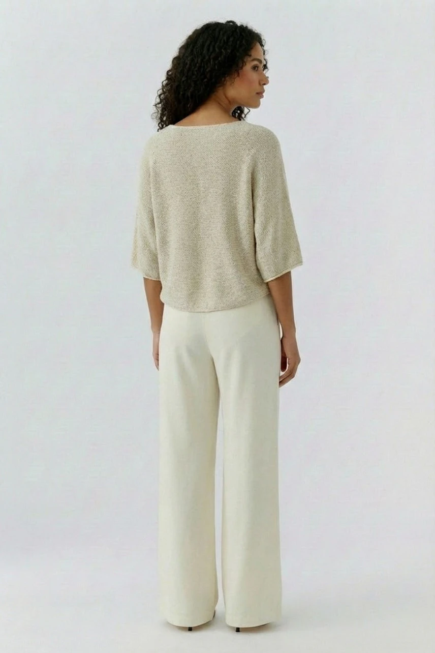 Bequemer Damen-Pullover: Frau mit lockigem Haar trägt einen hellen, lässigen Pullover und weite Hosen.