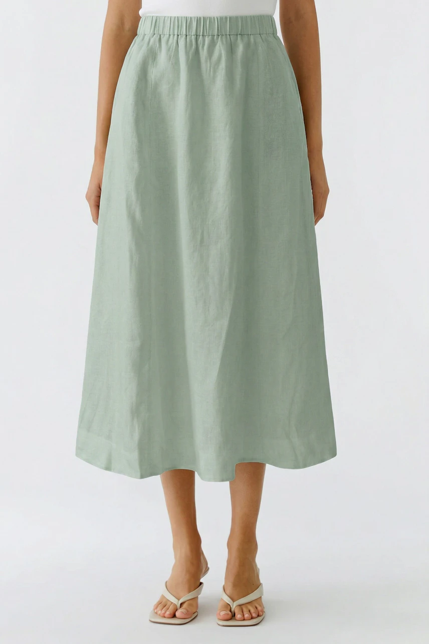 Woman in a light green A-line skirt, standing with sandals. Casual and comfortable look.
