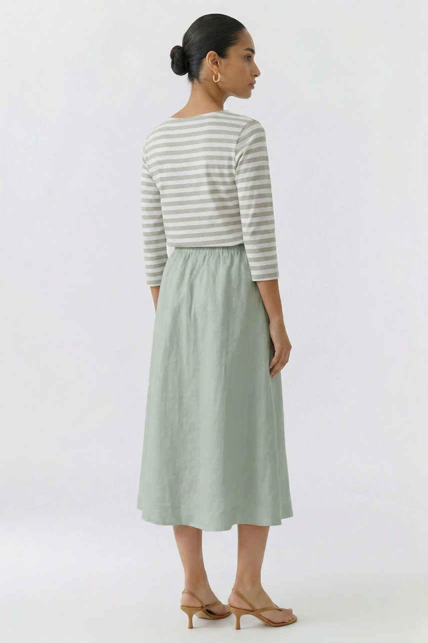 Casual A-line skirt: Woman in a green A-line skirt and matching top, viewed from the back.