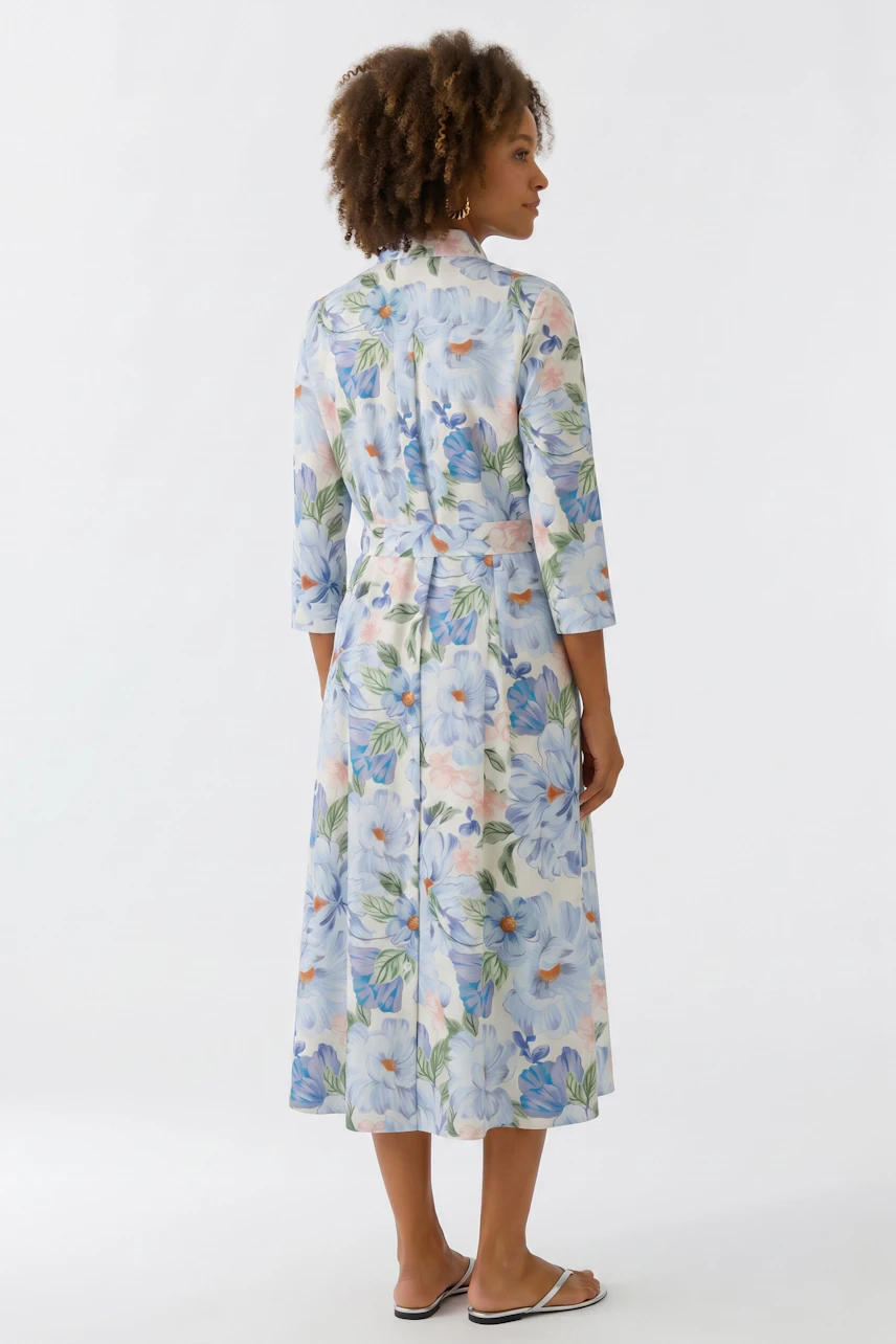 Frau im floralen Midikleid mit langen Ärmeln, Rückansicht. Leicht und sommerlich, ideal für warme Tage.